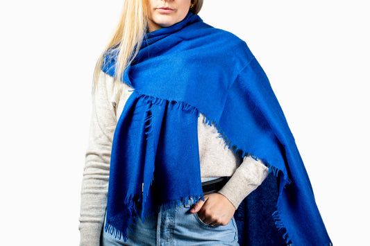 Person wearing a blue cashmere scarf on a white background