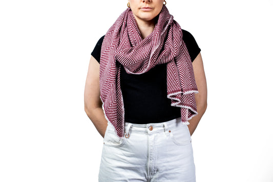 Person wearing a black top and white pants with a pink and red patterned pashmina scarf on a white background- GRIHA