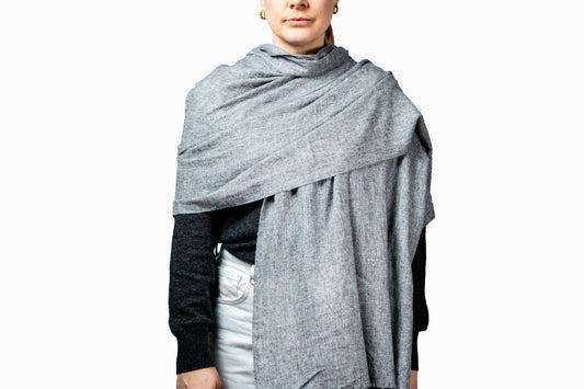Person wearing a gray pashmina over a black top on a white background