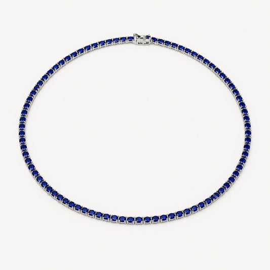 A tennis necklace featuring dark blue square-cut stones set in silver-toned metal, arranged in a circle on a plain white background.