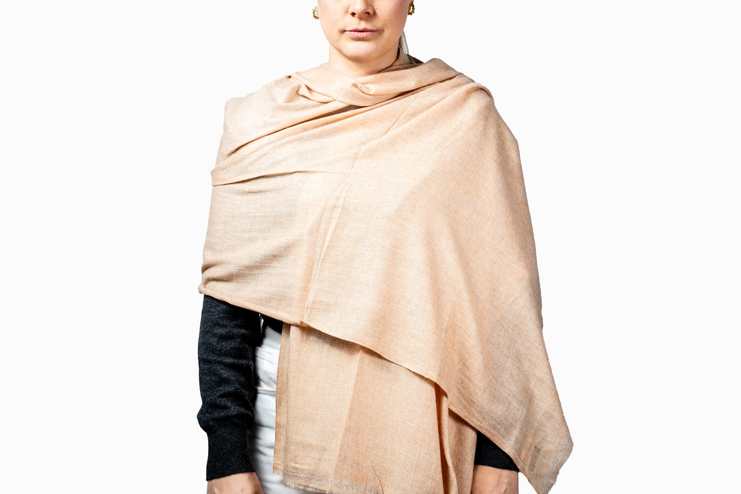 Person wearing a soft peach shawl pashmina on a white background