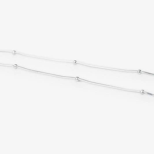 A delicate silver chain necklace featuring evenly spaced, small polished round beads, shown against a clean white background.