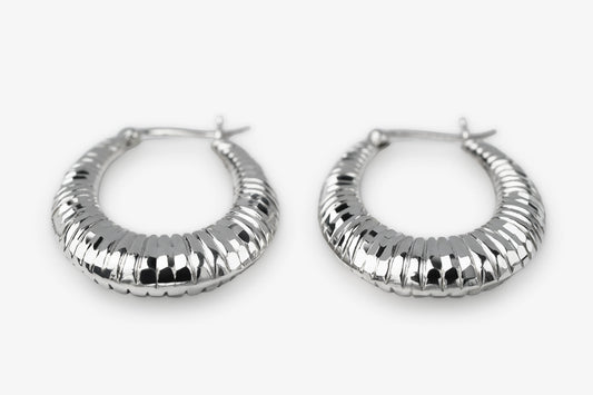 A pair of textured silver hoop earrings with a ribbed, segmented design, displayed on a clean white background.