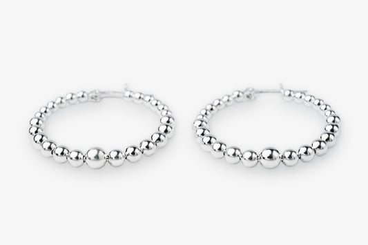 A pair of silver beaded hoop earrings with a polished metallic finish, displayed on a clean white background.