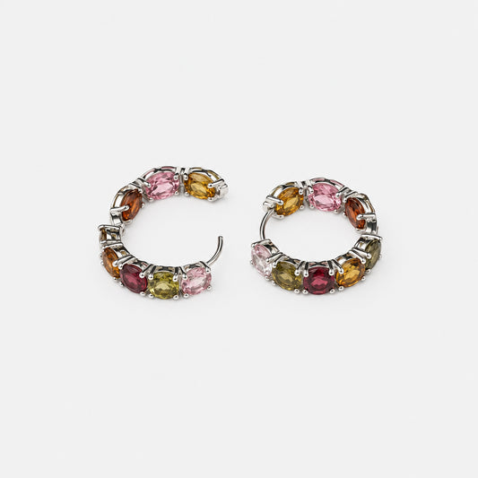 A pair of small silver-toned hoop earrings with multiple small round gemstones in pink, yellow, green, and burgundy, photographed on a plain white background.