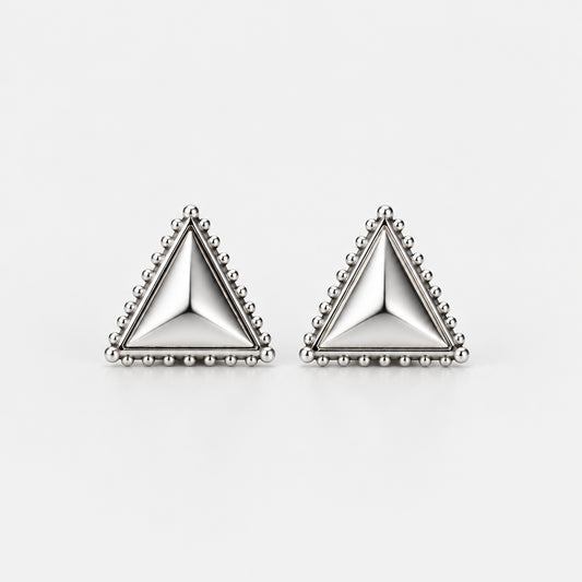 A pair of silver triangle stud earrings with beaded borders, resting on a light gray surface with soft shadows.