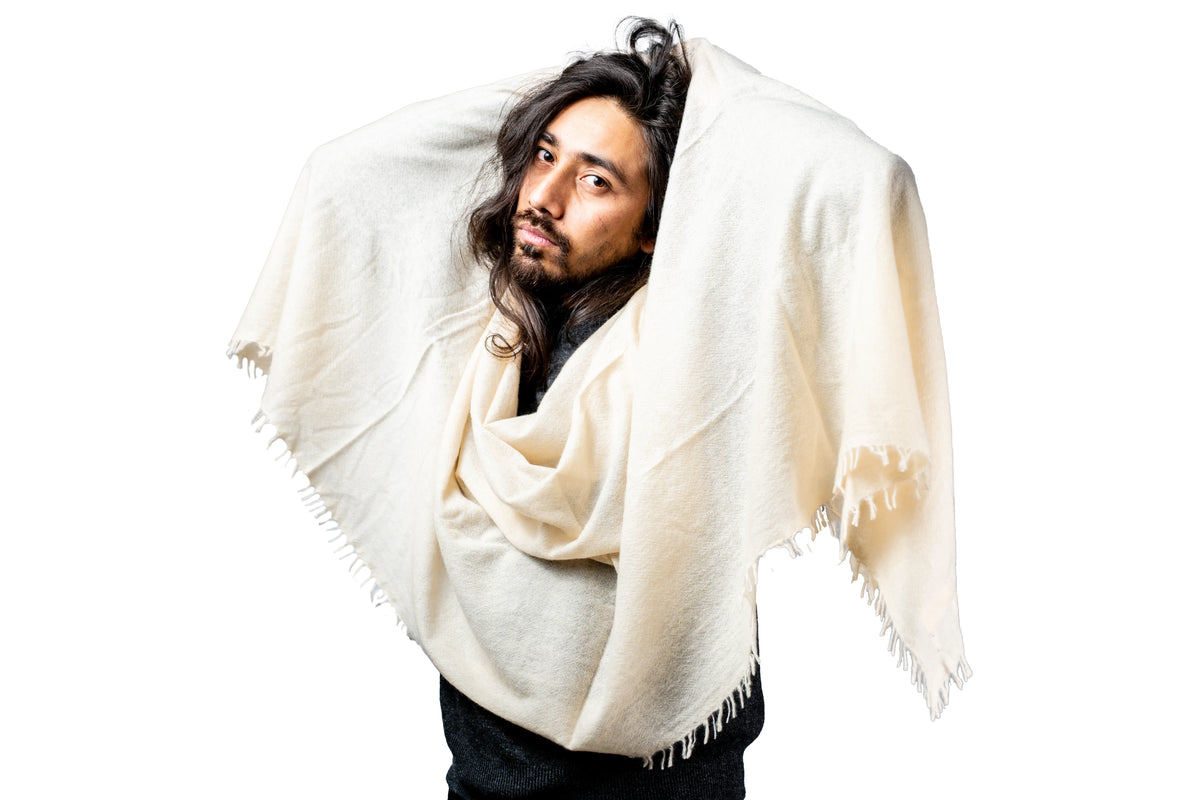 Man wearing a white cashmere shawl against a white background