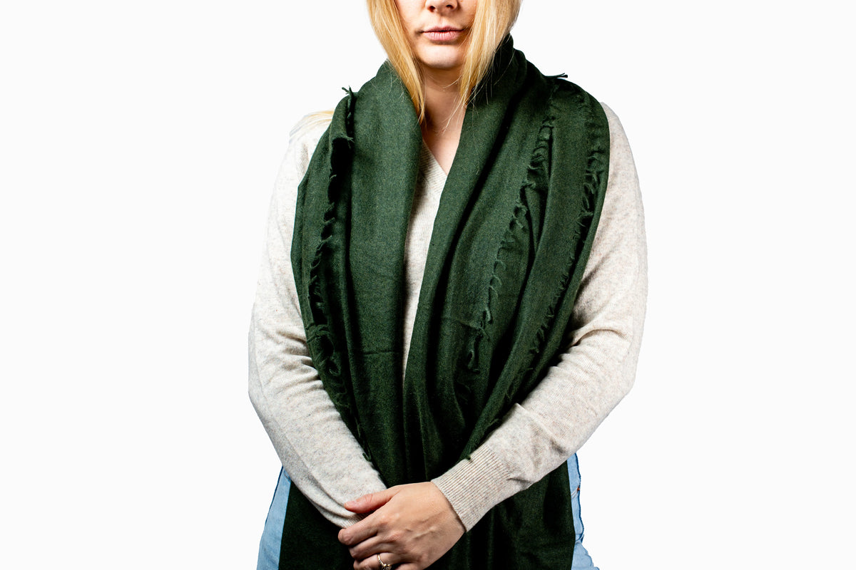 Woman wearing a green scarf and light gray sweater on a white background