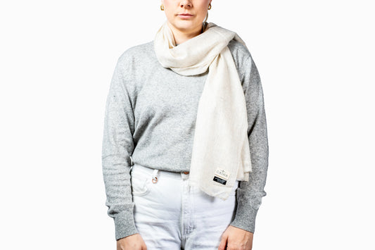 Person wearing a gray sweater and white scarf with a visible brand logo on a white background