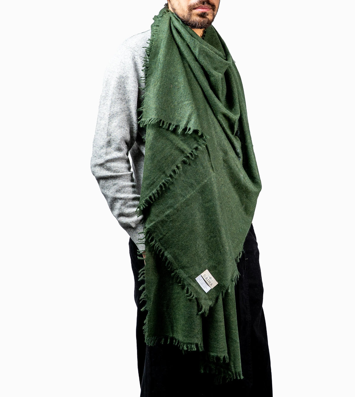Person wearing a green cashmere scarf with a brand label on a white background