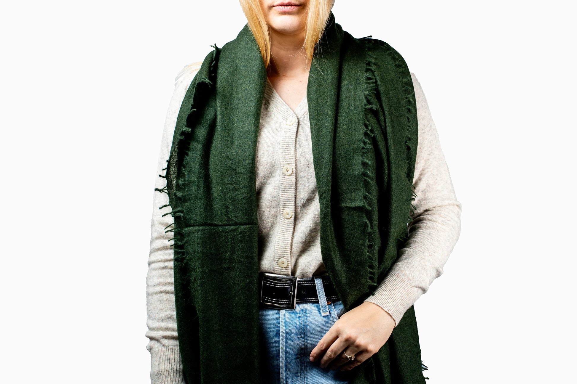 Person wearing a cashmere green scarf, light-colored shirt, and blue jeans on a white background