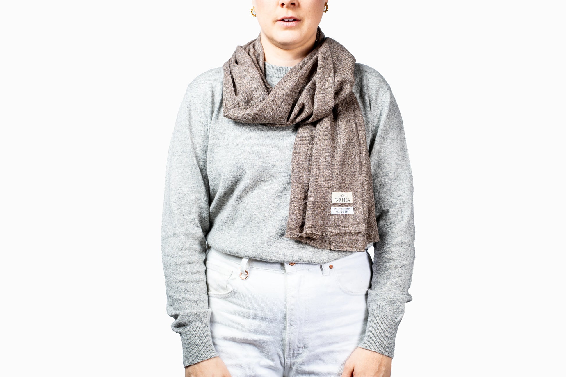 Person wearing a gray sweater and pashmina scarf on a white background