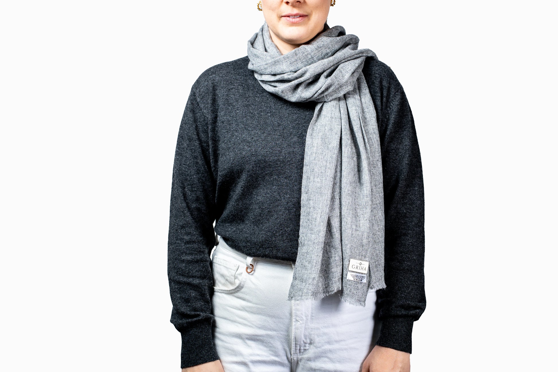 Person wearing a grey pashmina scarf with a visible brand logo on a white background