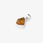 A polished silver pendant featuring a raw, faceted citrine gemstone, shown on a clean light gray background.