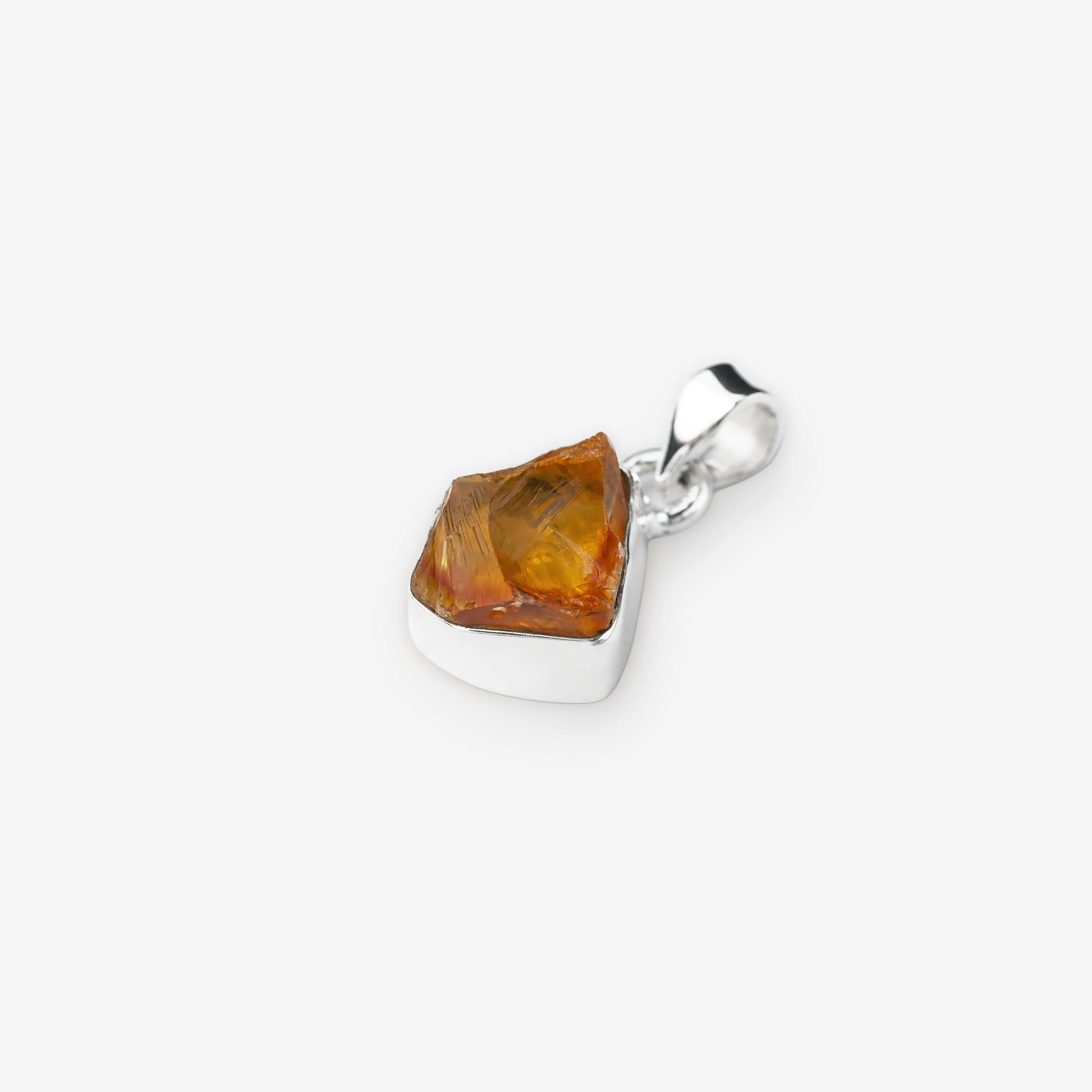 A polished silver pendant featuring a raw, faceted citrine gemstone, shown on a clean light gray background.