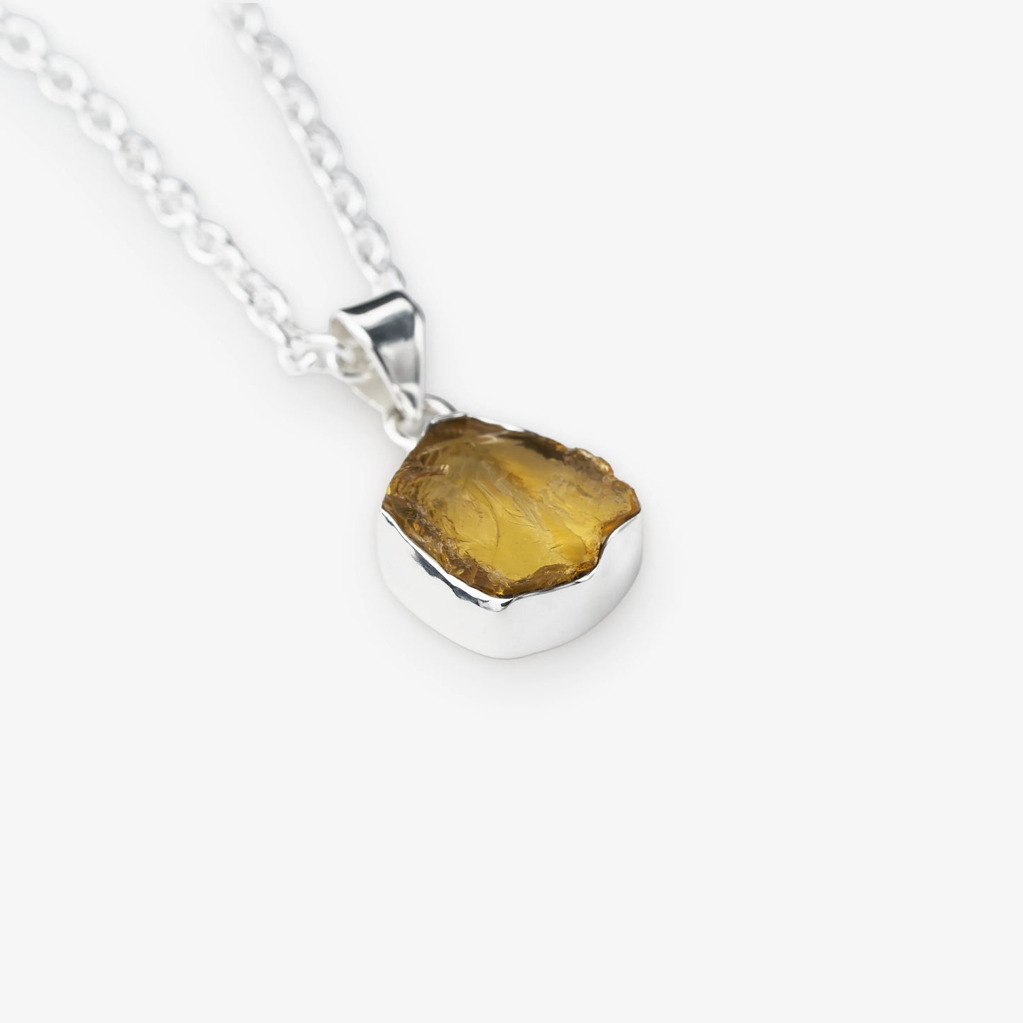 A silver chain necklace with a polished sterling silver pendant holding a raw, irregular-cut yellow citrine gemstone, shown on a light gray background.