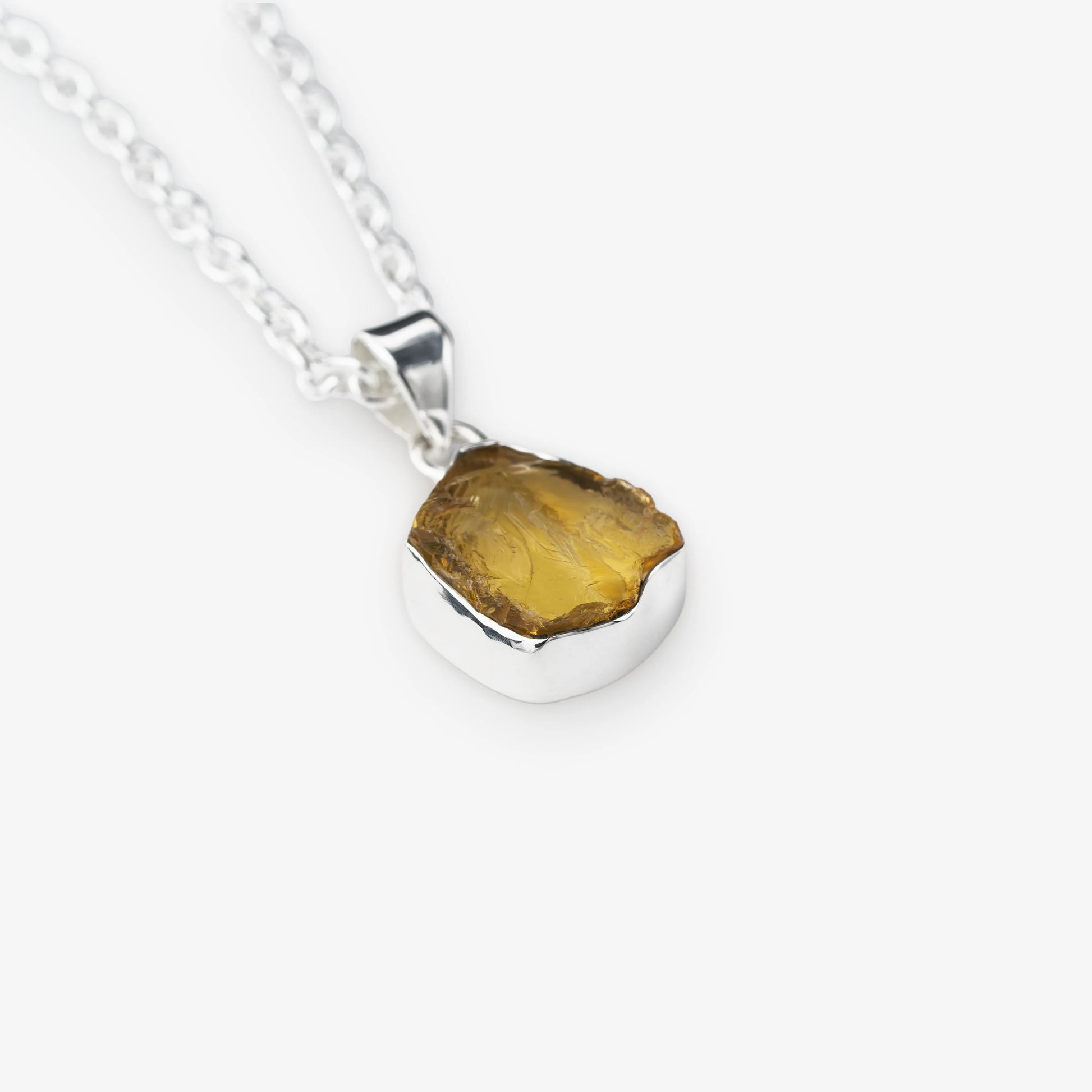 A silver chain necklace with a polished sterling silver pendant holding a raw, irregular-cut yellow citrine gemstone, shown on a light gray background.