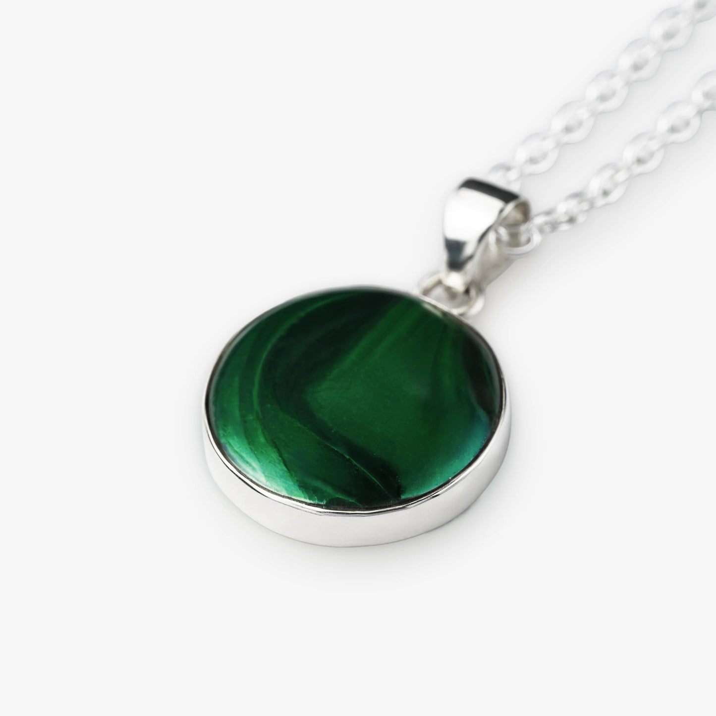 A silver round pendant necklace featuring a polished green malachite stone with natural swirling patterns, suspended from a silver chain on a light gray background.