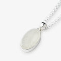 An oval pendant necklace featuring a milky white, iridescent moonstone set in a polished silver bezel, suspended from a silver chain against a light gray background.