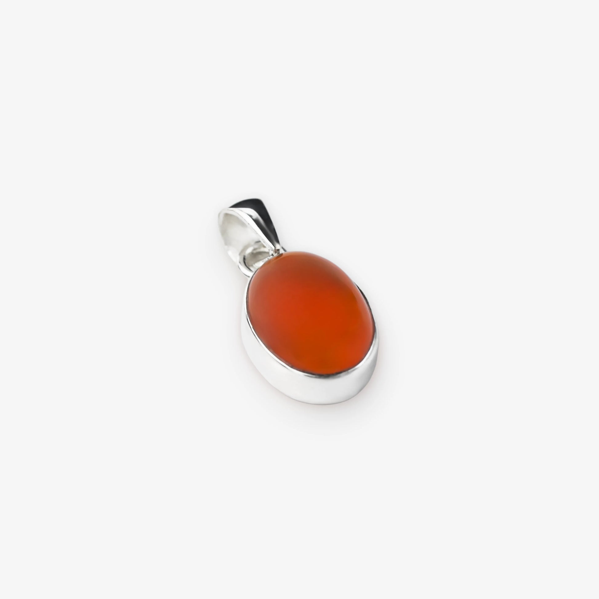 A silver pendant featuring a smooth, polished oval carnelian stone in a vibrant reddish-orange hue, set against a clean, light gray background.