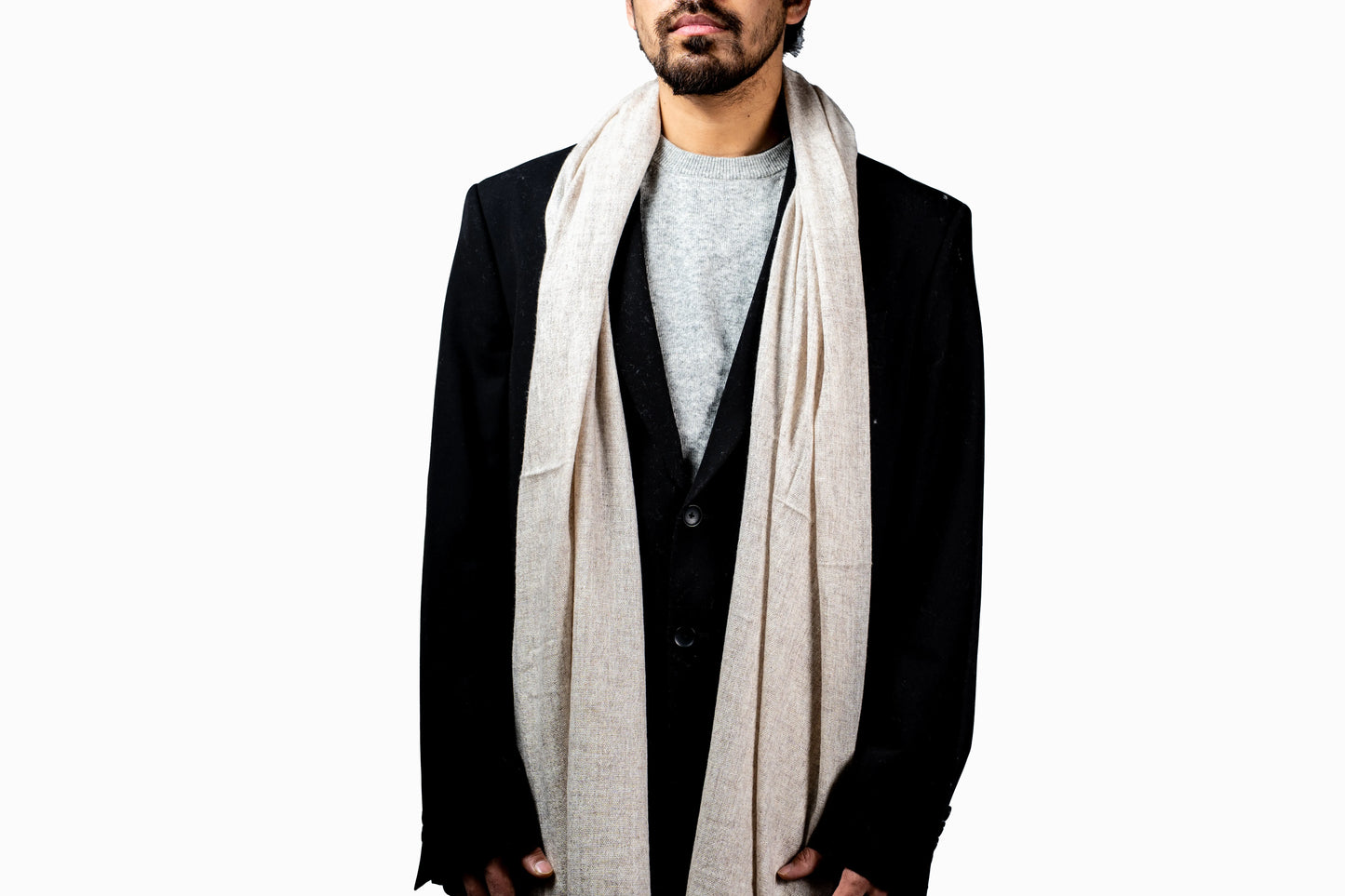 Man wearing a black blazer, gray shirt, and beige scarf on a white background