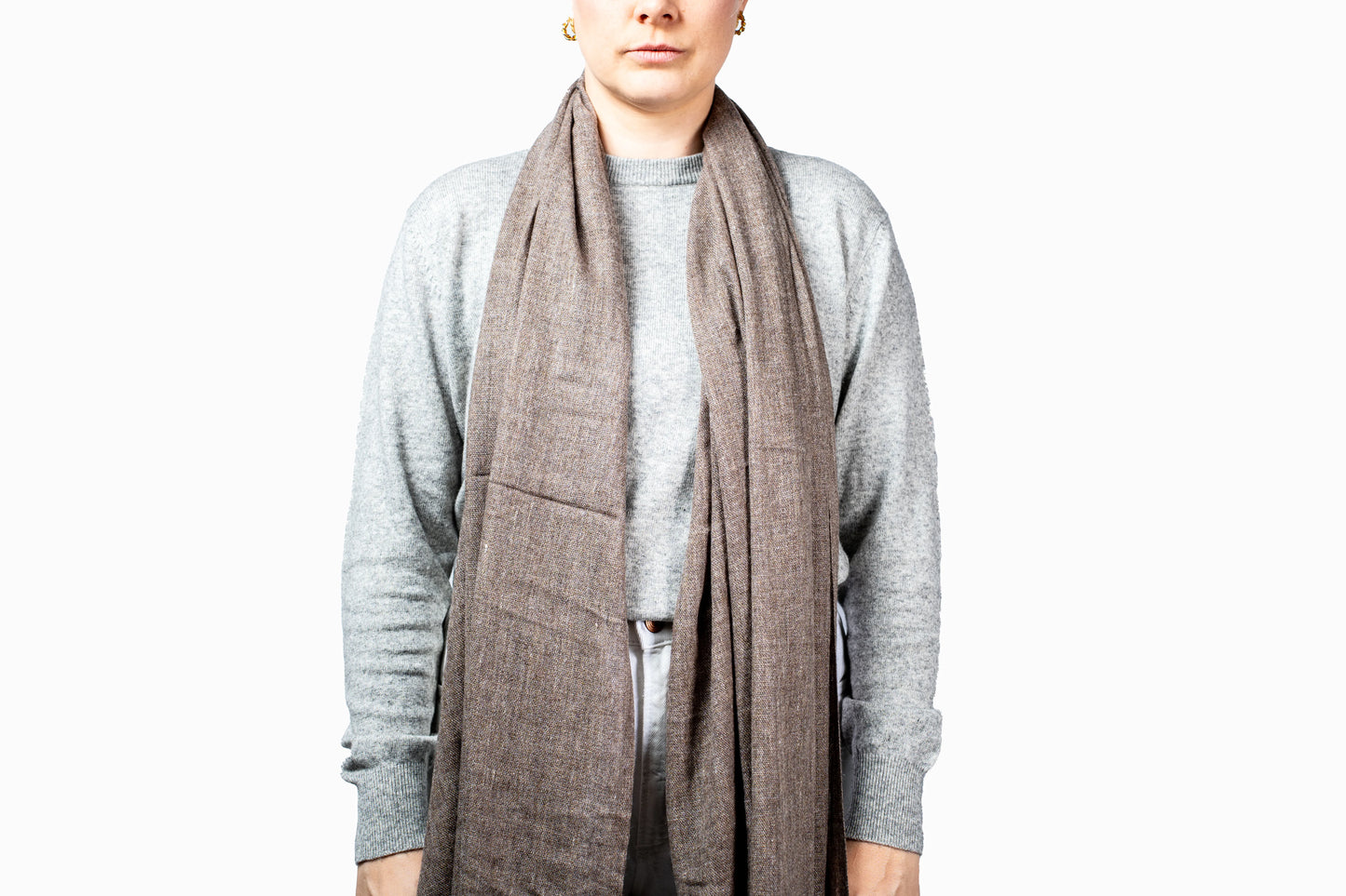 Person wearing a gray scarf and gray sweater on a white background