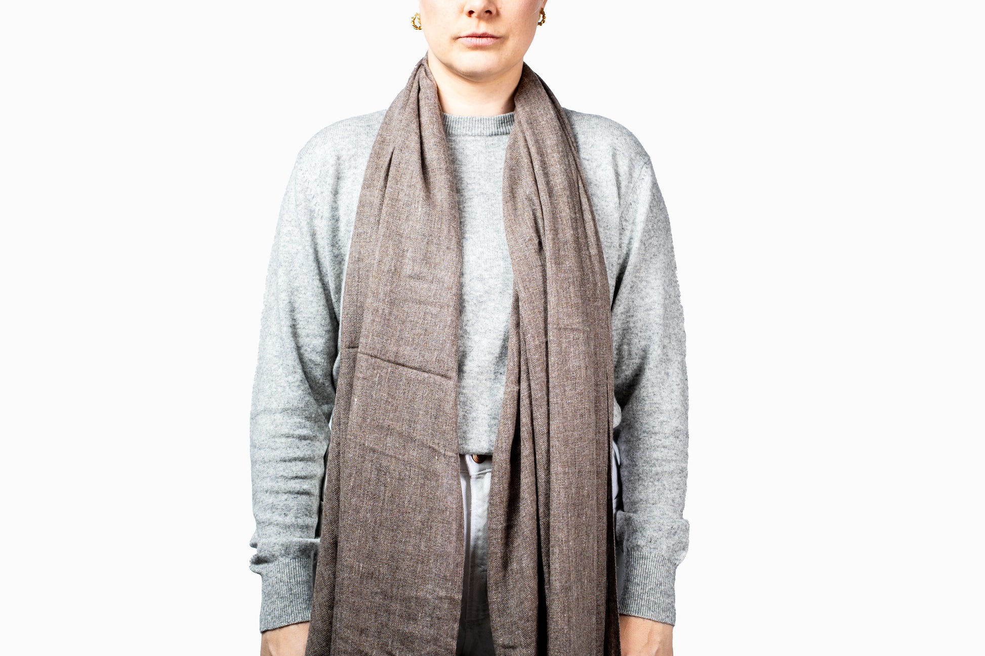 Person wearing a gray scarf and gray sweater on a white background