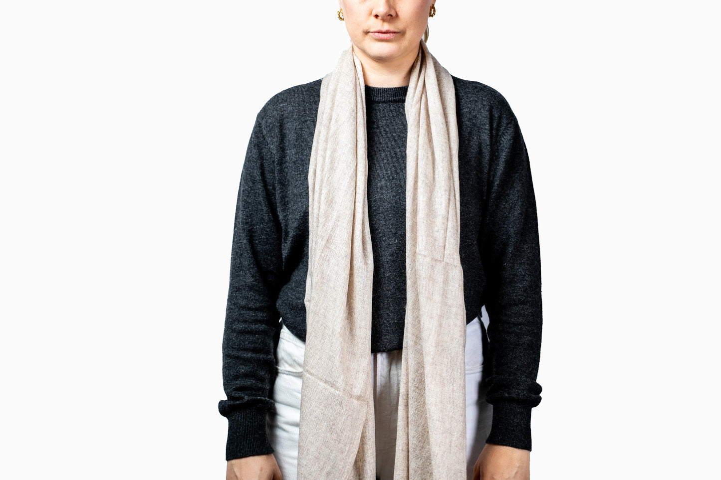 Person wearing a beige pashmina scarf with a plain background