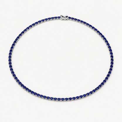 A tennis necklace featuring dark blue square-cut stones set in silver-toned metal, arranged in a circle on a plain white background.