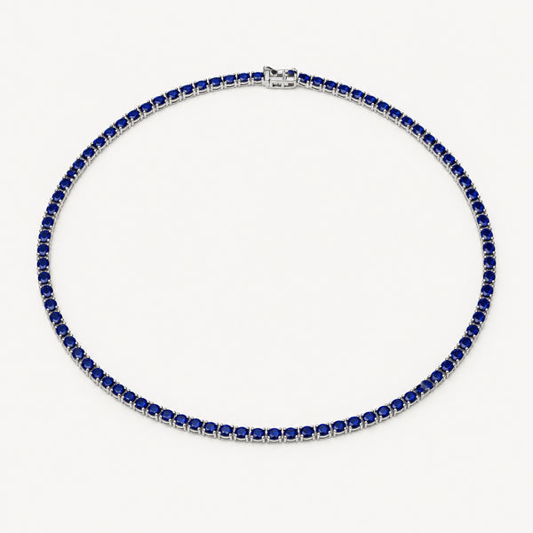 A tennis necklace featuring dark blue square-cut stones set in silver-toned metal, arranged in a circle on a plain white background.