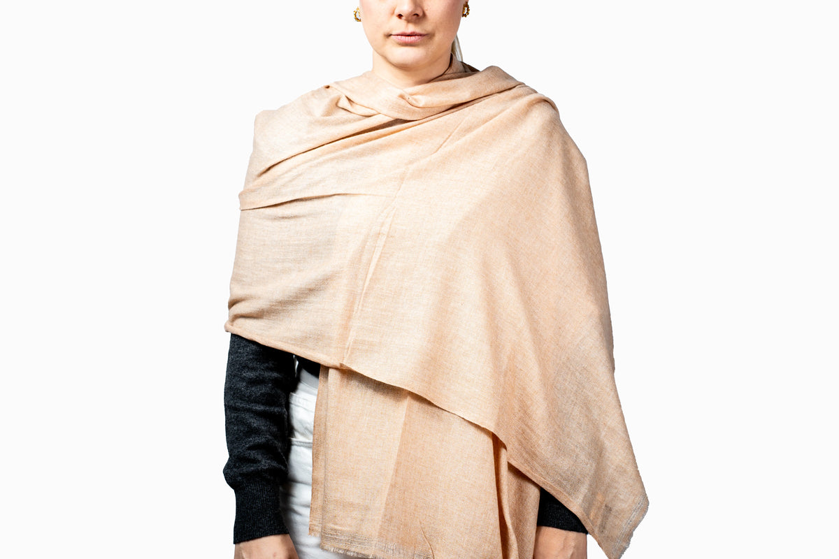 Person wearing a soft peach shawl pashmina on a white background