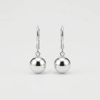A pair of polished silver leverback earrings with smooth, spherical drop charms, shown against a clean, light gray background.