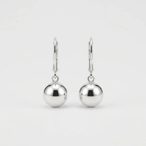 A pair of polished silver leverback earrings with smooth, spherical drop charms, shown against a clean, light gray background.