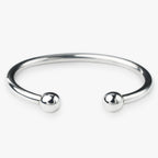 Silver bangle with two spherical beads on a white background