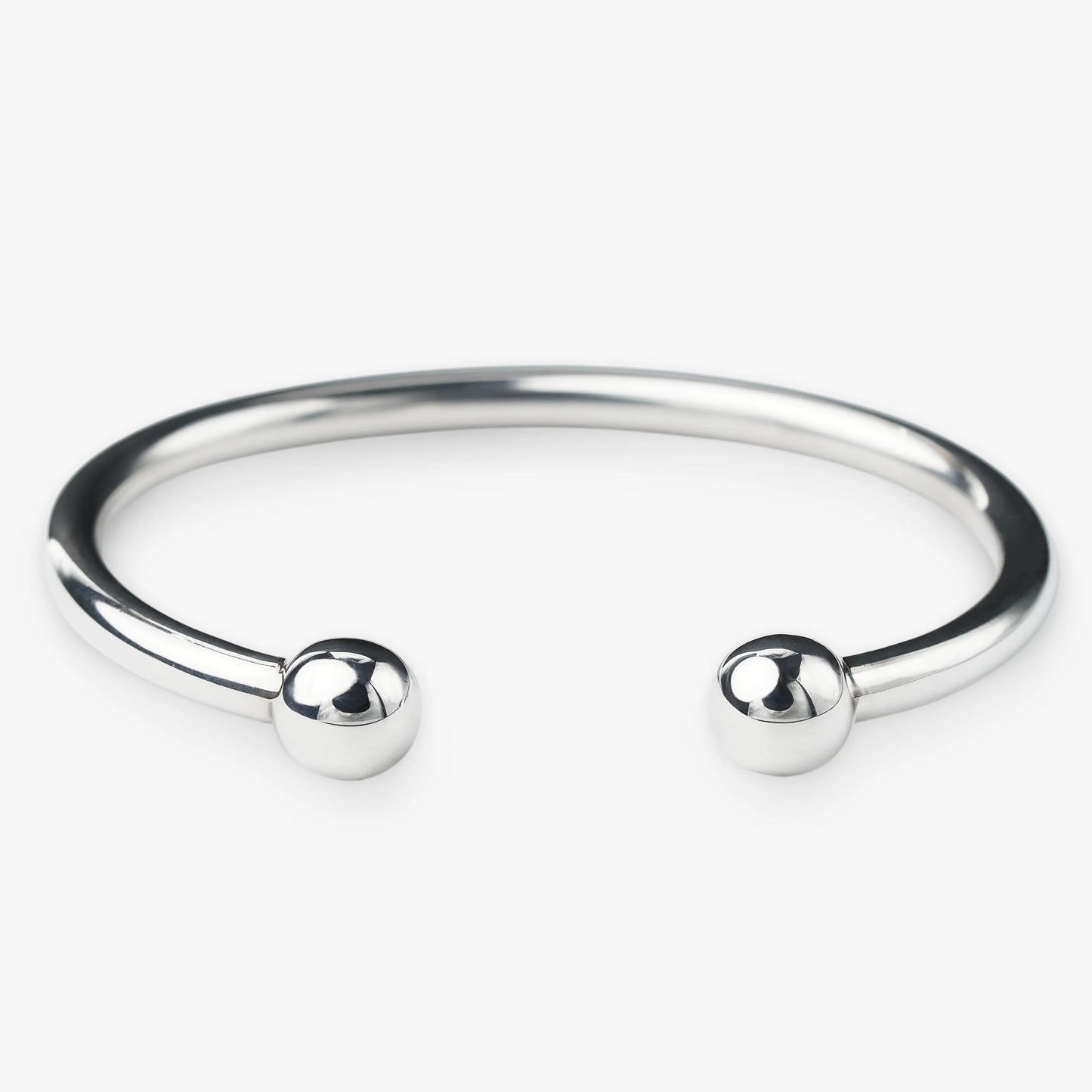 Silver bangle with two spherical beads on a white background