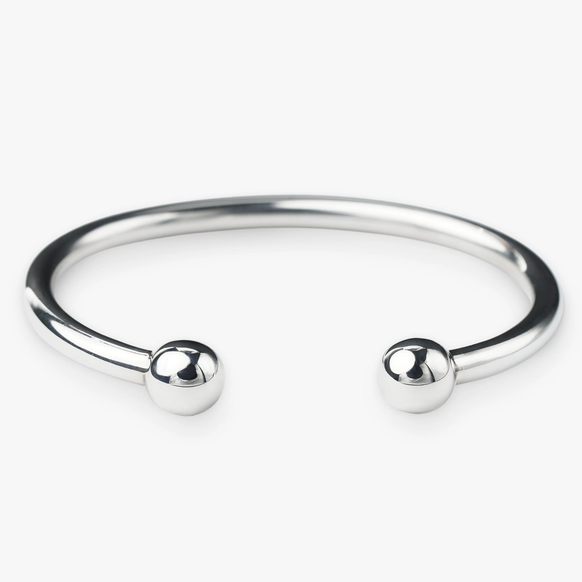 Silver bangle with two spherical beads on a white background