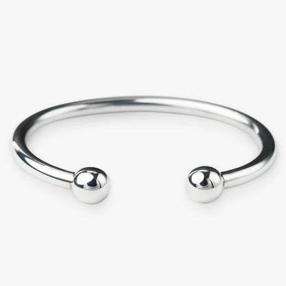 Silver bangle with two spherical beads on a white background