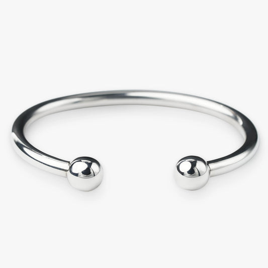 Silver bangle with two spherical beads on a white background