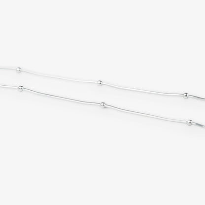 A delicate silver chain necklace featuring evenly spaced, small polished round beads, shown against a clean white background.