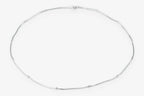 A delicate silver chain necklace arranged in a loose circle on a plain white background.
