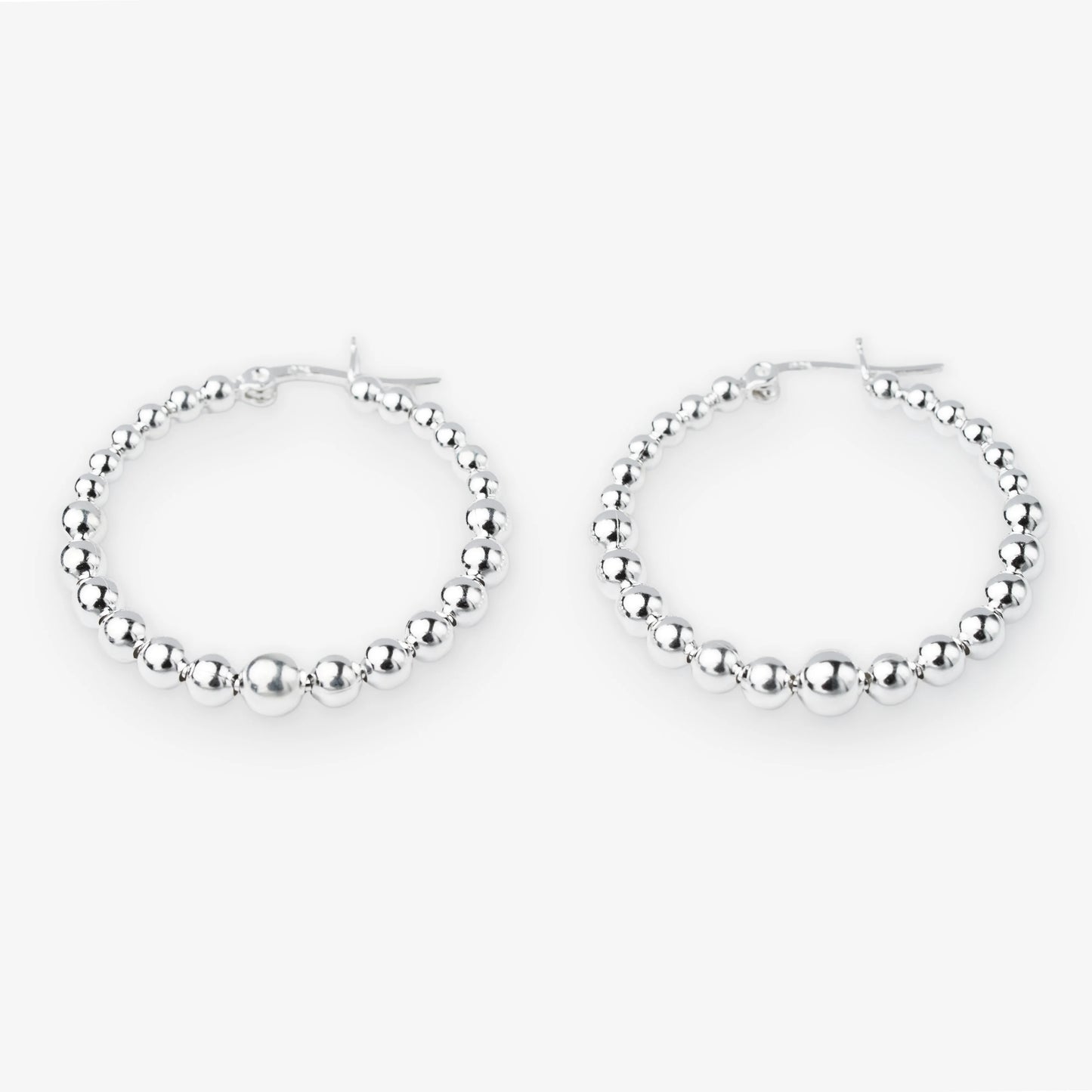 A pair of silver hoop earrings with a beaded, textured design, displayed against a clean white background.