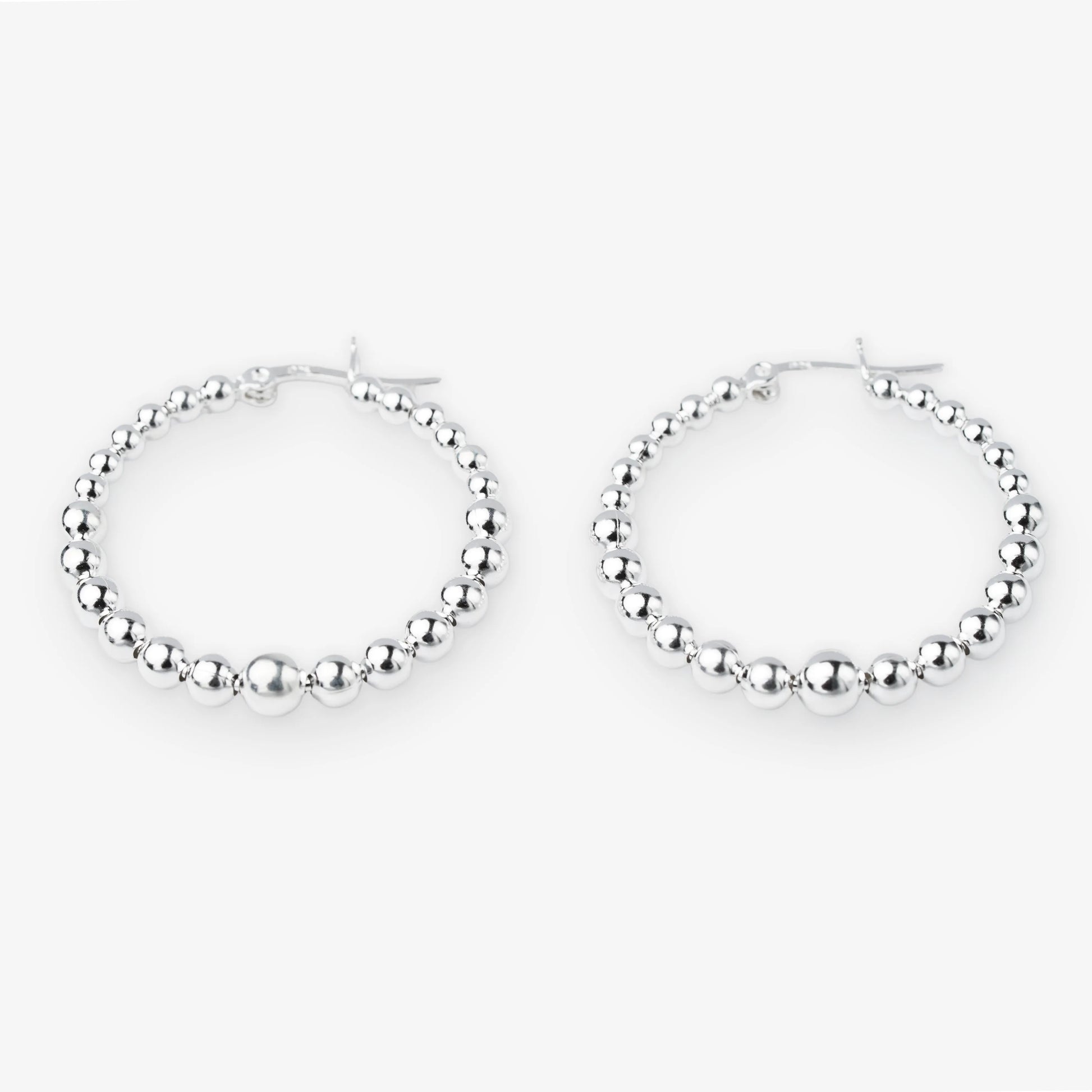 A pair of silver hoop earrings with a beaded, textured design, displayed against a clean white background.