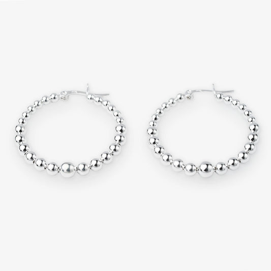 A pair of silver hoop earrings with a beaded, textured design, displayed against a clean white background.