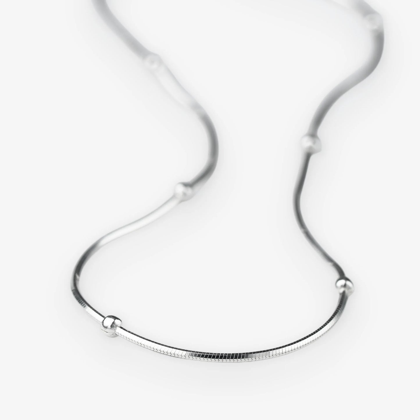 A silver snake chain necklace with small, evenly spaced spherical bead accents, displayed on a clean white background.