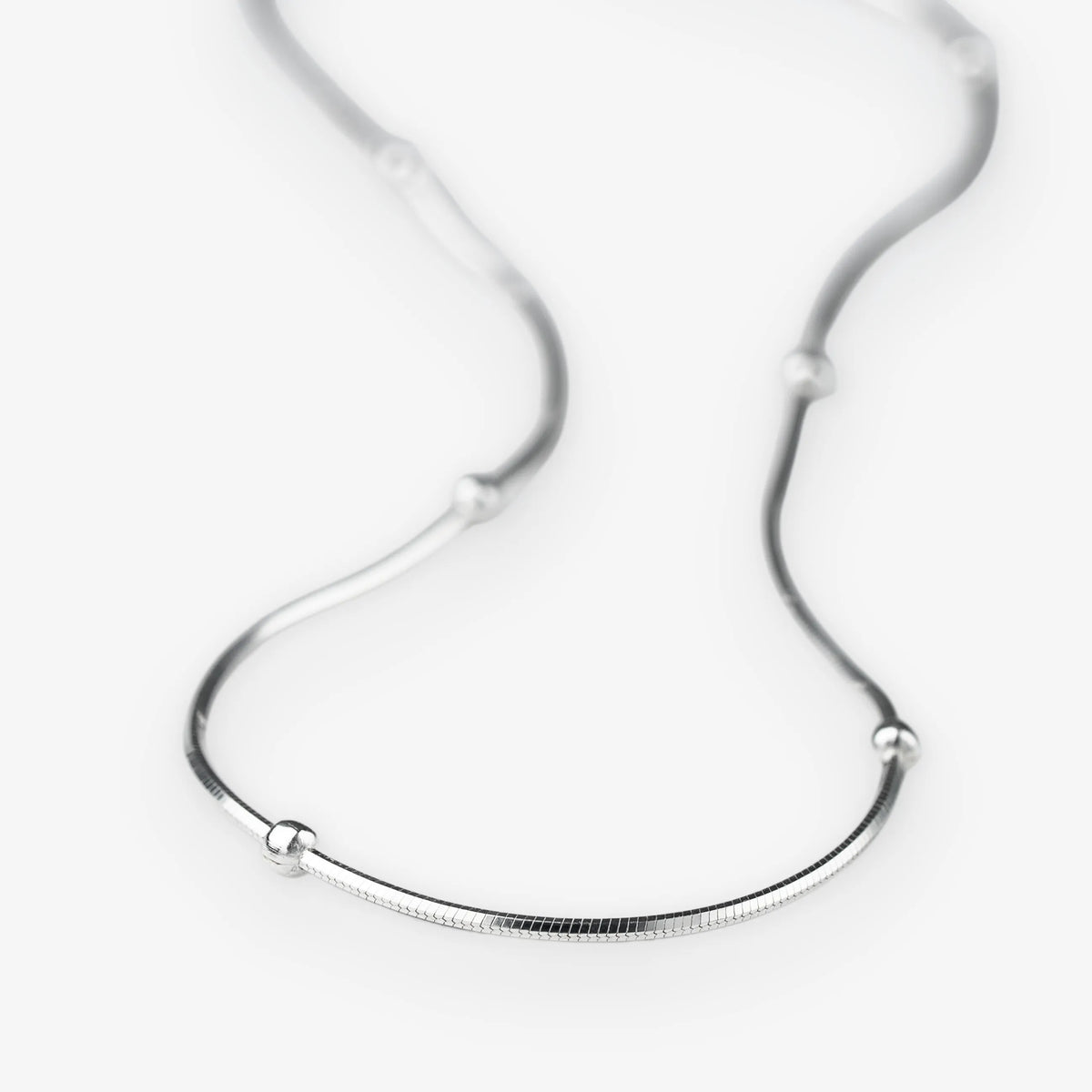 A silver snake chain necklace with small, evenly spaced spherical bead accents, displayed on a clean white background.