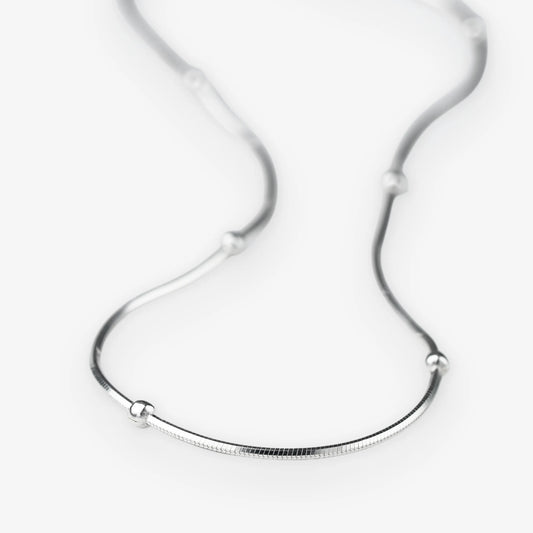 A silver snake chain necklace with small, evenly spaced spherical bead accents, displayed on a clean white background.
