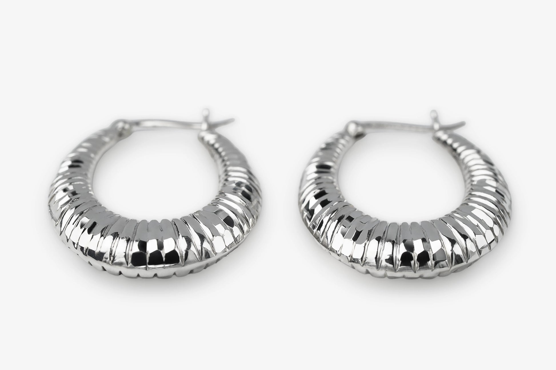 A pair of textured silver hoop earrings with a ribbed, segmented design, displayed on a clean white background.