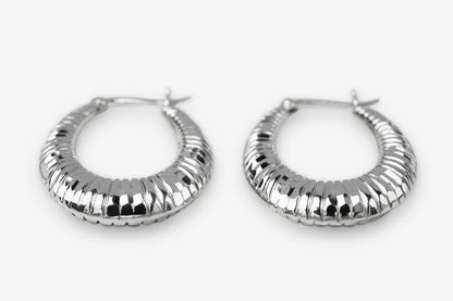 A pair of textured silver hoop earrings with a ribbed, segmented design, displayed on a clean white background.