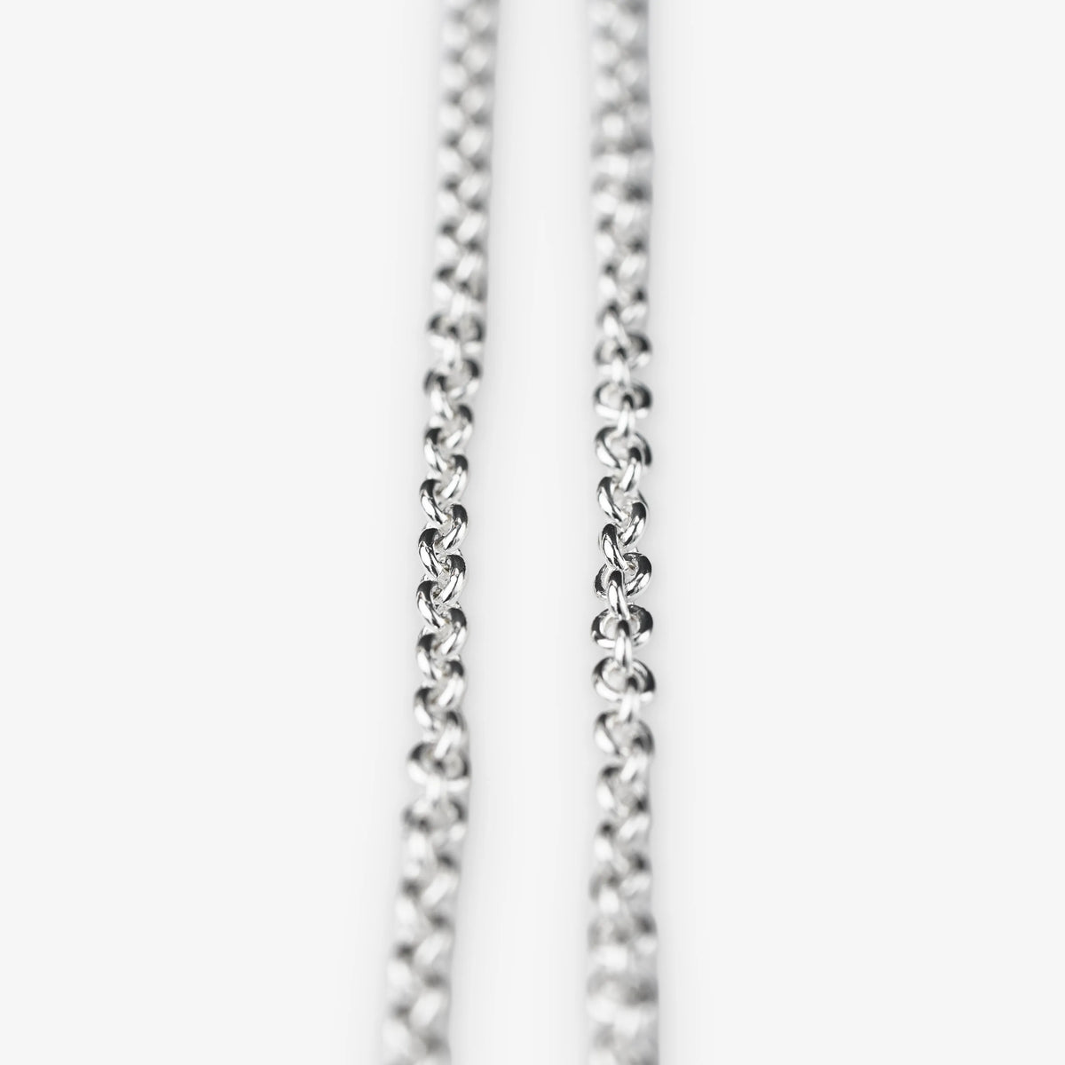 A close-up of a sterling silver belcher chain necklace against a plain white background.