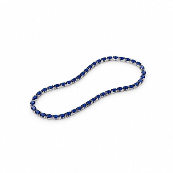A tennis-style necklace with dark blue oval gemstones set in a silver-toned metal, photographed on a plain light background.